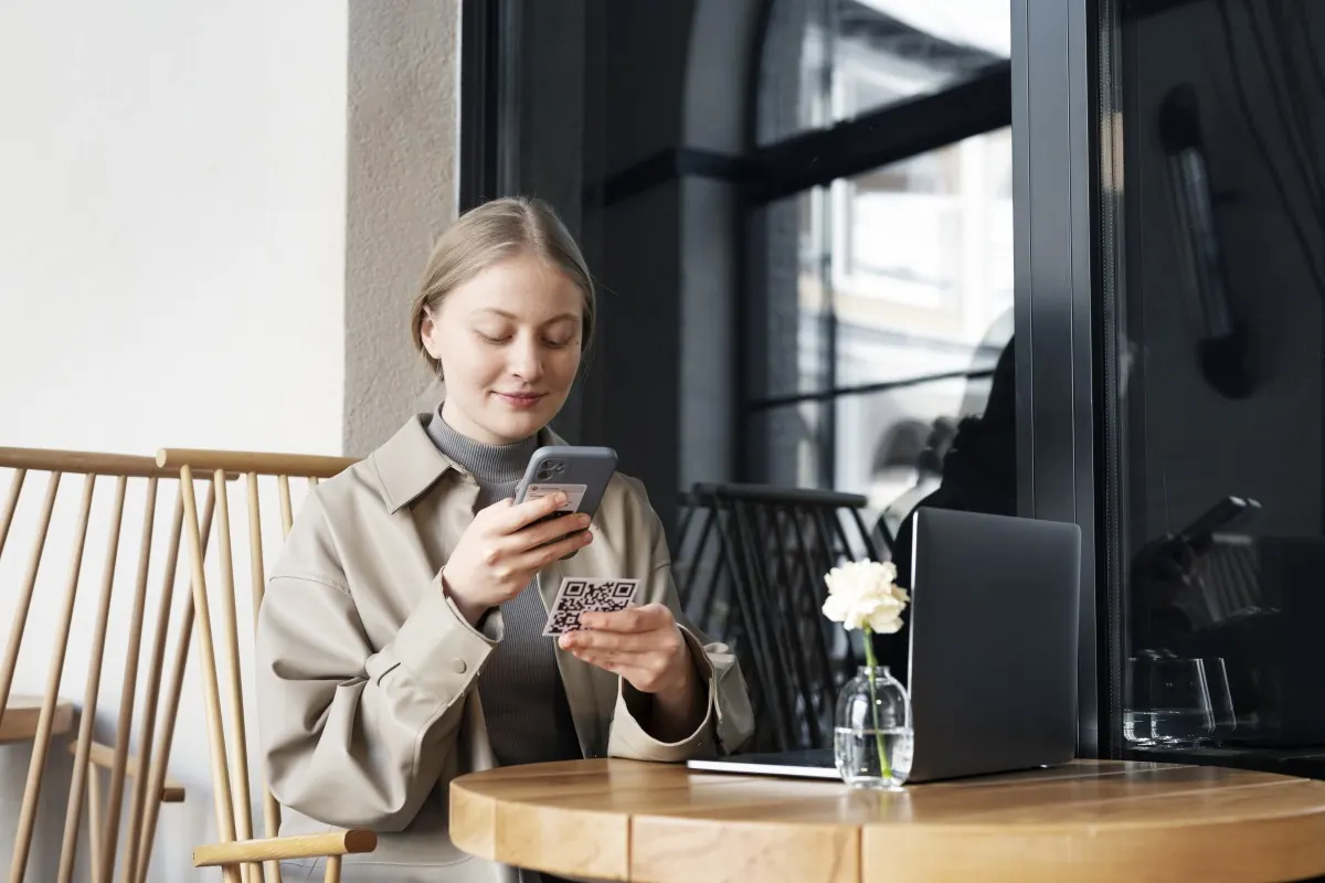 Guest scanning a table QR code in a sunny café with food on the table